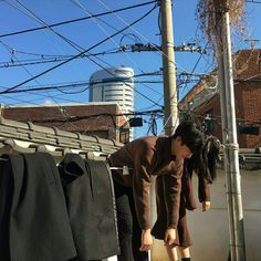 a woman bending over to pick up clothes from a rack on top of a roof