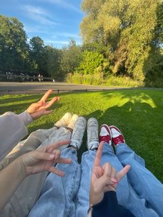 two people sitting in the grass making peace signs