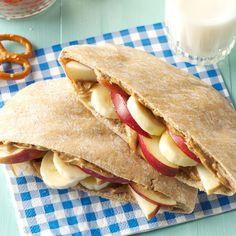 two pita sandwiches with apples and pretzels on a blue checkered napkin