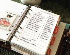 an open planner book sitting on top of a table next to a coffee mug and other items