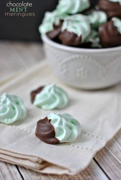 four pieces of chocolate with green frosting on a white cloth next to a bowl