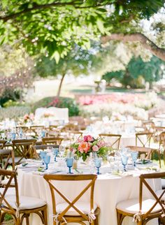 the table is set with white linens and flowers in vases on each side