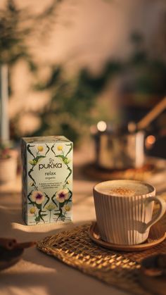 a cup of coffee sitting on top of a table next to a box of pukka