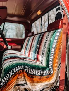 the interior of an old truck with colorful blankets on it