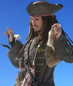 a man with dreadlocks and a pirate hat holding something in his right hand