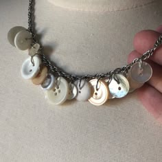 a person holding onto a necklace with buttons on the front and back of it's chain