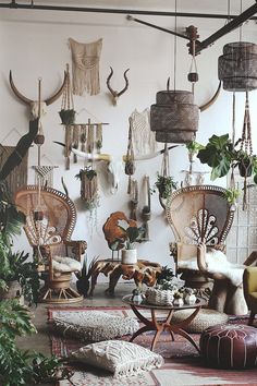 a living room filled with lots of plants and hanging decorations on the wall above it