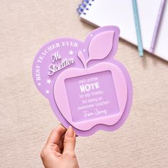 a person holding up an apple shaped notepad