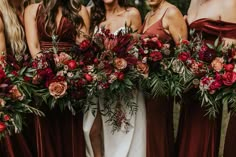 a group of women standing next to each other holding bouquets filled with flowers and greenery