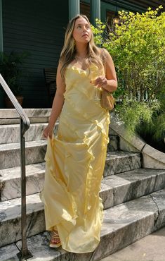 a woman in a yellow dress is standing on some steps