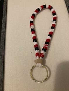 a red, white and black beaded keychain with a metal ring hanging from it