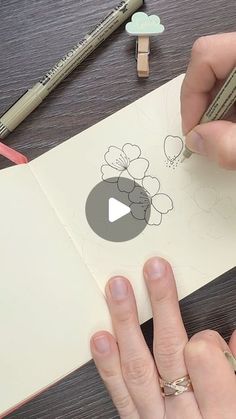 someone is drawing flowers on a piece of paper