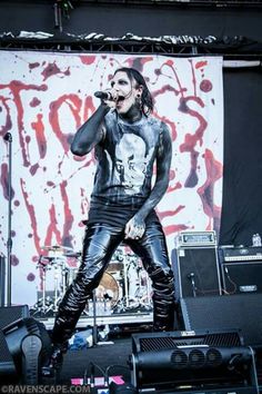 a man standing on top of a stage next to a microphone and amps in front of him