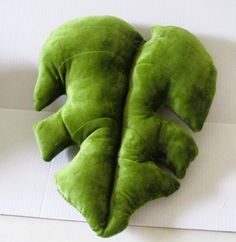 two green stuffed animals laying on top of a white surface with one facing the camera