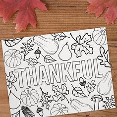 a thanksgiving coloring page with leaves and acorns on a wooden table next to it