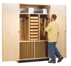 a man standing in front of a wooden storage cabinet with drawers and file folders