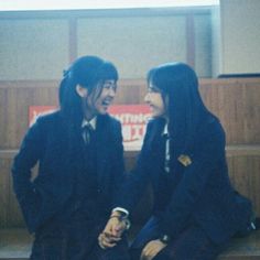 two young people sitting on the steps talking to each other in front of a window