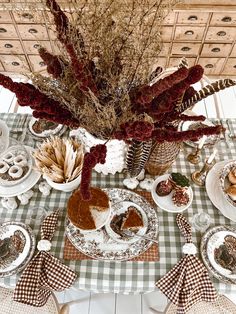 a table topped with plates and dishes covered in fall leaves, dried flowers and pumpkins