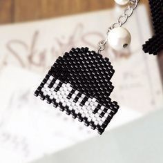 a pair of black and white beaded earrings hanging from a chain on top of a piece of paper