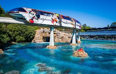 a monorail going over the water with mickey mouse characters on it's side