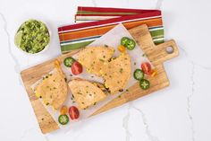 two quesadillas on a cutting board next to a bowl of guacamole