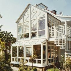 a large white house sitting on top of a lush green hillside next to a forest