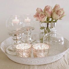 a tray with candles and vases on top of it next to some pink roses