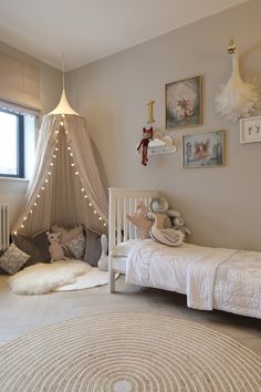 a bedroom with a white bed and some pictures on the wall next to a window