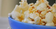 a blue bowl filled with popcorn on top of a table