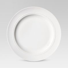 a white plate with beaded edges on a plain surface, ready to be eaten