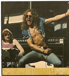 a man with long hair sitting next to a woman in front of a keyboard and microphone