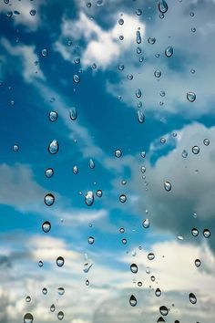 rain drops on the window with blue sky and clouds in the background