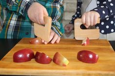 two children are cutting apples on a wooden board