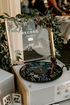 an old record player sitting on top of a white table next to a plant and window