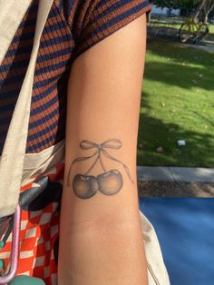 a woman with a tattoo on her arm that has two cherries attached to it