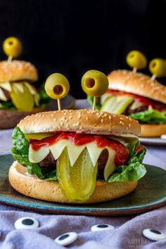 two cheeseburgers with pickles and olives on a blue plate, ready to be eaten