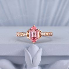 a pink diamond ring sitting on top of a white box