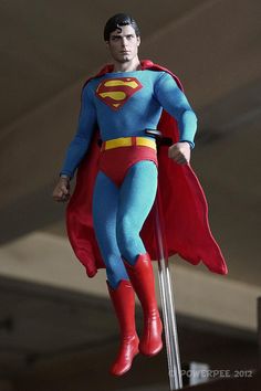 a superman action figure is suspended from the ceiling with his red cape and blue suit