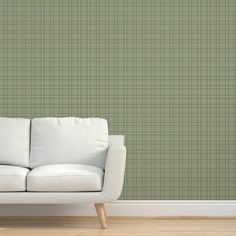 a white couch sitting in front of a wall with a green checkered pattern on it