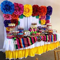 a table topped with lots of colorful desserts and flowers on top of it's sides