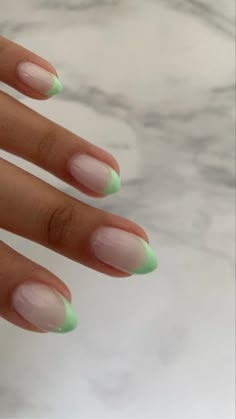 a woman's hand with green and white manies on her nails, against a marble background