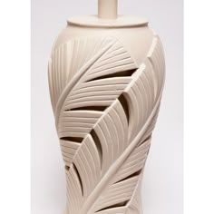 a white vase with an intricate design on the front and sides, sitting against a white background