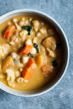 a bowl of soup with carrots, cauliflower and spinach in it