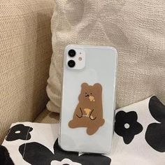 an iphone case with a bear sticker on it sitting next to a flowered pillow