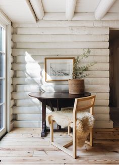 a table and chair in a room with wood floors, white walls and beams on the ceiling