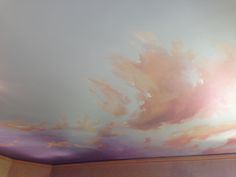 the ceiling is painted with pink clouds and blue sky in an otherwise empty room,