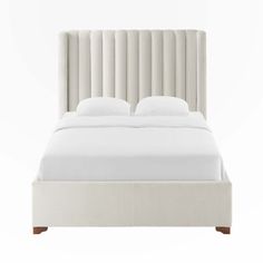 a white bed with an upholstered headboard and two pillows on the bottom