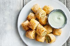 a white plate topped with pastries next to a bowl of ranch dressing on top of a wooden table