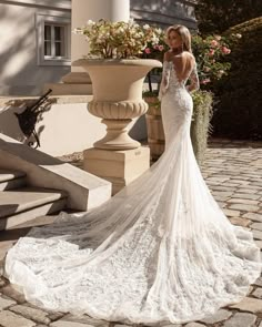 a woman in a wedding dress is standing on the steps near a planter with flowers