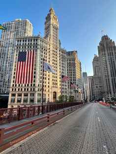 an empty city street in front of tall buildings with american flags on the top and bottom